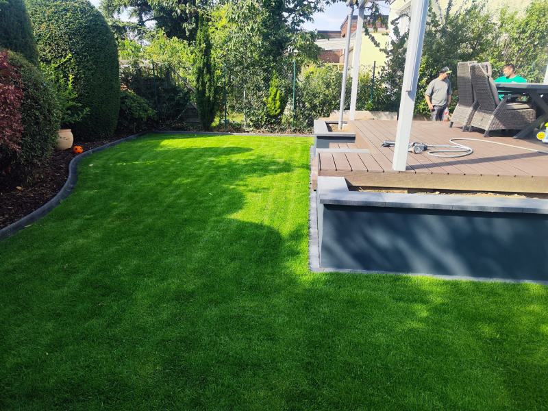 Fertiger Garten in Sankt Augustin: frisch verlegter Rollrasen vor der neuen Holzterrasse mit dunkler Einfassung